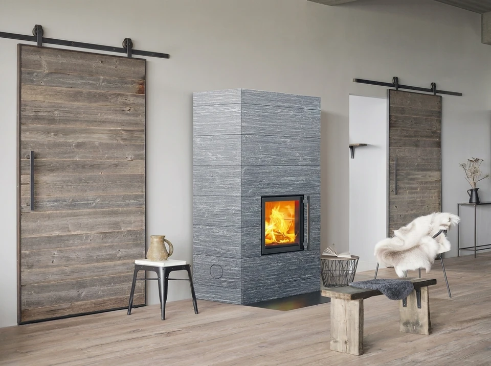 Salon moderne avec insert à bois encastré dans un habillage en pierre naturelle schisteuse gris anthracite, couvrant toute la hauteur du mur
